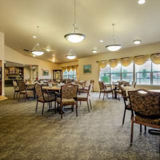 A spacious dining room with multiple tables and chairs, featuring large windows and elegant lighting.