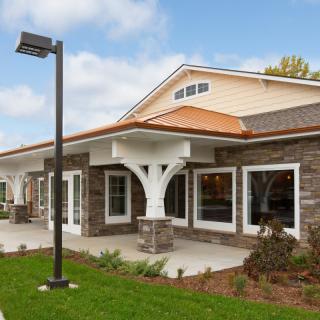 A modern residential building with stone and wood facade surrounded by a landscaped area.