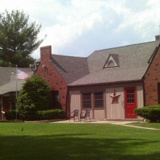 A quaint brick house with a well-maintained lawn and red front door.