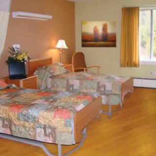 A hospital room with two beds and a window letting in natural light.