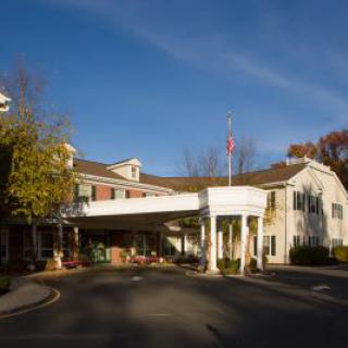 A hotel entrance with a covered driveway surrounded by autumn trees.