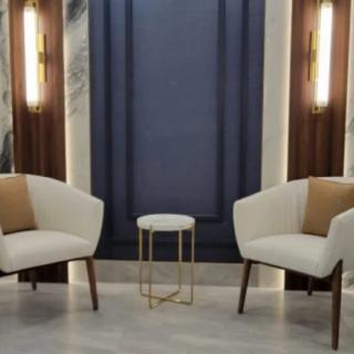 A modern, minimalist seating area with two chairs and a small side table.