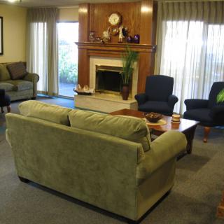 A cozy living room with a fireplace, surrounded by comfortable sofas and chairs.