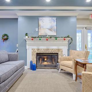 A cozy living room with a fireplace, sofa, and armchairs arranged for comfort.