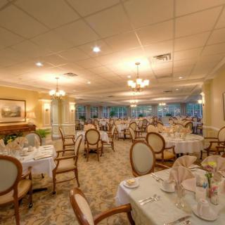 An elegant dining room with neatly arranged tables and chairs, featuring ambient lighting and tasteful decor.