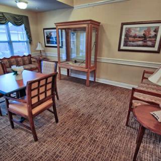 A cozy living room with armchairs, a table, and decorative artwork on the walls.