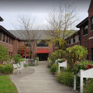 A serene courtyard featuring brick buildings and lush greenery.
