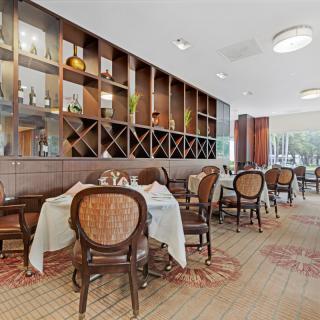 A cozy restaurant interior featuring neatly arranged tables and chairs with decorative shelving on the wall.