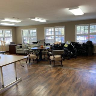 A spacious room with several chairs and tables, lit by natural light from the windows.