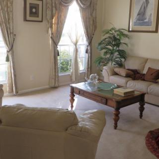 A cozy living room with elegant decor, featuring sofas, a coffee table, and large windows with curtains.