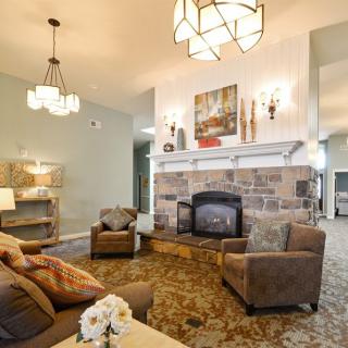A cozy living room with a stone fireplace, comfortable seating, and elegant lighting fixtures.