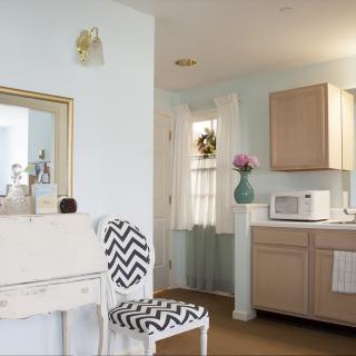 A cozy kitchen corner with a chevron-patterned chair, wooden cabinets, and a vase of flowers.