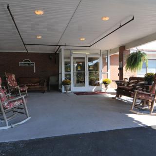 An inviting entrance featuring outdoor rocking chairs under a covered area.