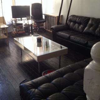 A modern living room with dark flooring, leather sofas, and a sleek coffee table.