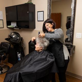 A hairdresser styles the hair of a senior client in a cozy salon setting.