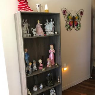 A cozy corner featuring a decorative shelf filled with various figurines and a colorful butterfly decoration on the wall.