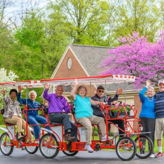 A group of people enjoying a ride on a multi-person bicycle on a sunny day.