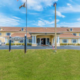 A hotel building with a welcoming entrance, surrounded by flags under a cloudy sky.