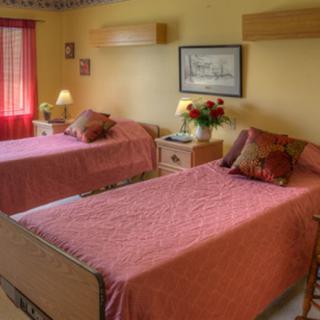 A cozy bedroom with two neatly made single beds, traditional decor, and soft lighting.