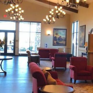 A spacious lobby area with comfortable seating, elegant chandeliers, and artwork on the walls.