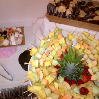 A colorful arrangement of fruit skewers and desserts displayed on a buffet table.