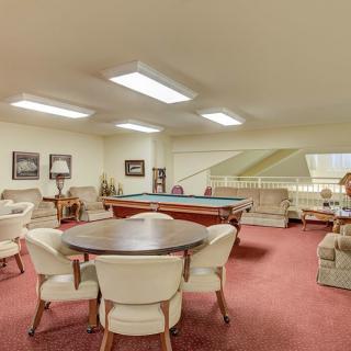 A spacious game room featuring a pool table and comfortable seating areas.