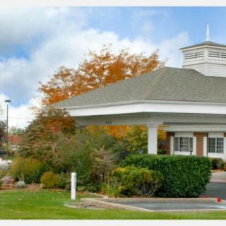 A cozy building surrounded by autumn foliage under a cloudy sky.