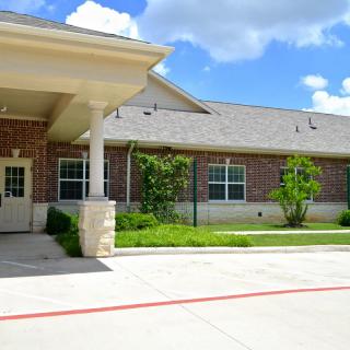 A brick building with a covered entrance and well-maintained landscaping.