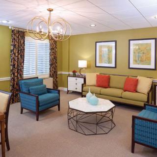 A cozy living room with a modern chandelier, colorful furniture, and wall art.