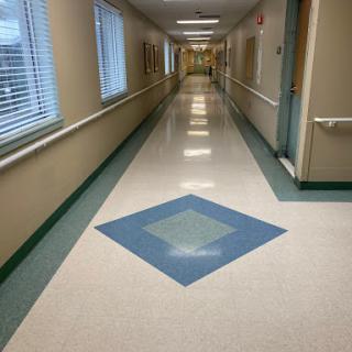 A well-lit corridor with a patterned floor and natural light from the windows.