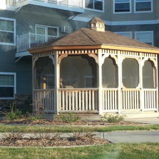 A charming wooden gazebo in front of a residential building.