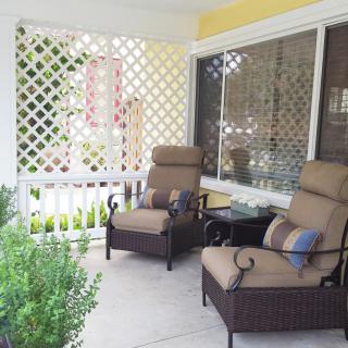 A cozy porch with comfortable chairs and a lattice backdrop, perfect for relaxation.