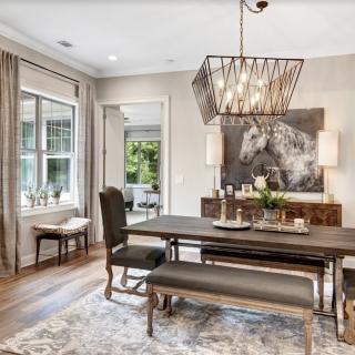A modern dining room with a wooden table, bench seating, and a stylish chandelier.