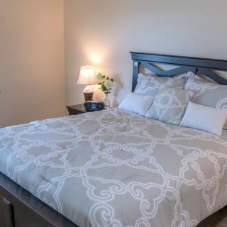 A neatly made bed with patterned bedding next to a nightstand with a lamp and decor.