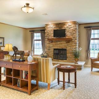 A cozy living room featuring a stone fireplace with a TV mounted above, surrounded by comfortable seating and elegant decor.