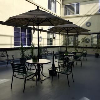 A cozy outdoor patio with tables, chairs, and umbrellas surrounded by a building exterior.