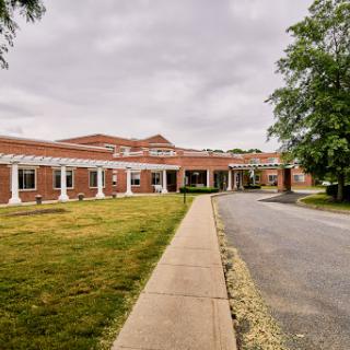 A view of a brick building with a landscaped area and a pathway leading to the entrance.