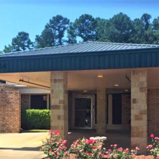 A sunny entrance to a building surrounded by colorful flowers.