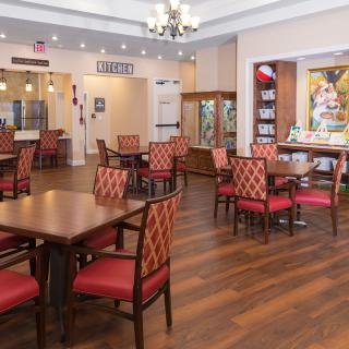 A well-appointed dining area featuring multiple tables and chairs, with elegant wooden flooring and a chandelier overhead.