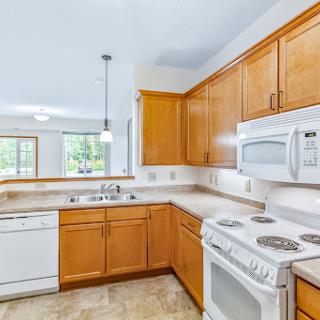 A modern kitchen featuring wooden cabinets, essential appliances, and ample natural light.