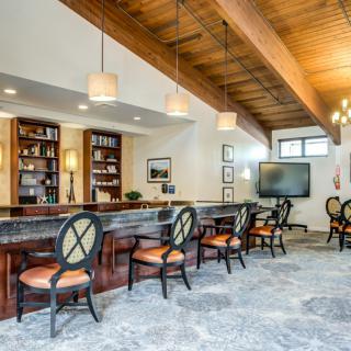 A modern dining area featuring a bar with elegant seating, wooden ceiling, and contemporary decor.