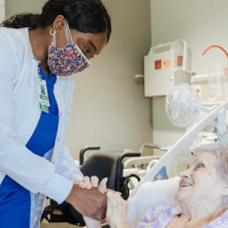 A nurse provides compassionate care to an elderly patient in a healthcare setting.