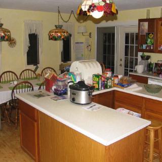A cozy kitchen and dining area featuring wooden cabinets, a central island with various kitchen items, and a dining table with chairs.