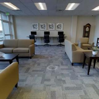 A spacious and modern lounge area designed for relaxation and work, featuring comfortable seating and computer stations.