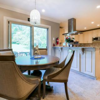 A modern kitchen and dining area with a round table, elegant chairs, and a pendant light.