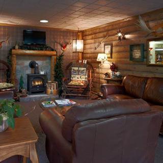 A cozy, rustic living room with wood paneling and a warm fireplace.
