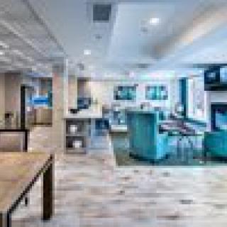 A modern and spacious lobby with comfortable seating and a television.