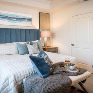 A cozy bedroom with modern decor, featuring blue accents and comfortable bedding.