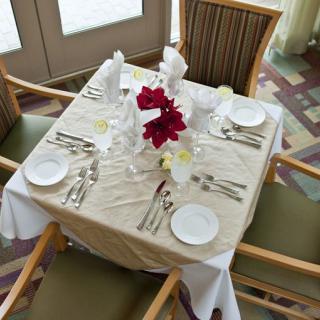An elegantly set dining table prepared for four, featuring neatly arranged cutlery and a floral centerpiece.