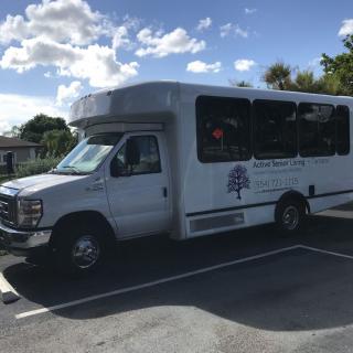A small shuttle bus parked in a lot under a clear sky.